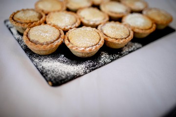 Close up delicious home baked seasonal frosted Christmas mince pies on slate plate on a buffet in a luxury hotel