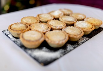 Close up delicious home baked seasonal frosted Christmas mince pies on slate plate on a buffet in a luxury hotel