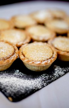 Close up delicious home baked seasonal frosted Christmas mince pies on slate plate on a buffet in a luxury hotel