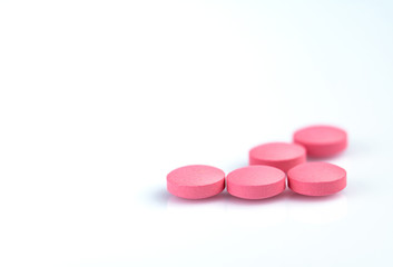 Round pink tablets pill on white background. Vitamins and minerals plus folic acid vitamin E and zinc in drug bottle on gradient background. Pink tablets pills for during and after pregnancy woman.