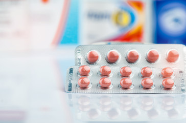 Round orange tablet pills in blister pack on doctor table or pharmacy counter. Drug use in daily...