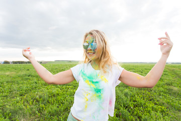 Fun, holi festival and holidays concept - Funny woman covered with color powder smiling over nature...