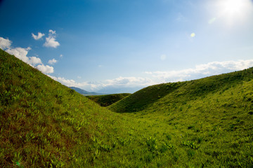 Beautiful spring and summer landscape. Lush green hills, high mountains. Spring blooming herbs. Mountain wild tulips. Blue sky and white clouds. Kyrgyzstan Background for tourism.