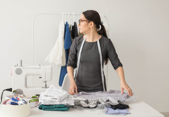Dressmaker, fashion designer and tailor concept - beautiful young stylist at workplace near rack...
