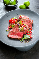 Traditional South American barbecue wagyu roast beef sliced with pico de gallo and salsa verde garnished as top view in a modern design plate