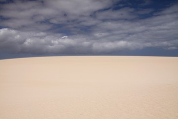 Fototapeta na wymiar Bright shining white edge of sand dune contrasting against deep blue sky, Corralejo, Fuerteventura, Canary Islands