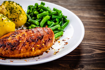 Grilled chicken fillet and vegetables on wooden table