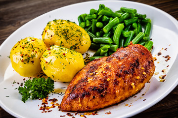 Grilled chicken fillet and vegetables on wooden table