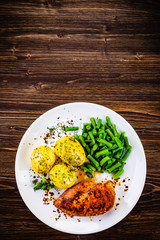 Grilled chicken fillet and vegetables on wooden table