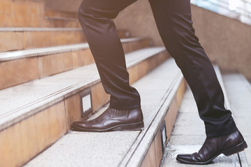 modern businessman working  close-up legs walking up the stairs in modern city. in rush hour to work in office a hurry. During the first morning of work. stairway. soft focus.