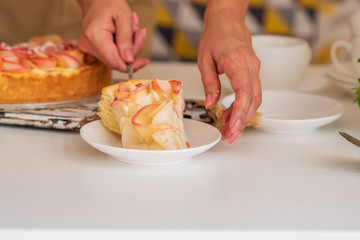 Woman cuts homemade apple cake, close-up. Pieces apple cake on a white wooden table. Delicious dessert.