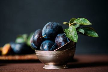 Bowl with ripe juicy plums on table. Fresh organic plums. Summer harvest. Autumn harvest. Beautiful still life. Toned image. Selective focus.