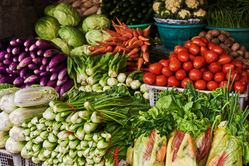 Asian food ingredients corner. Organic fresh agricultural product at farmer market. Fresh tomatoes, onions, eggplant, are packaged in simple containers and displayed for sale at an produce stand.
