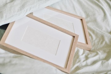 Mockup-template. Single wooden photo frame in pastel green bed. Frames with white copy space, cozy feeling ideal for furniture/decoration shoot-outs.