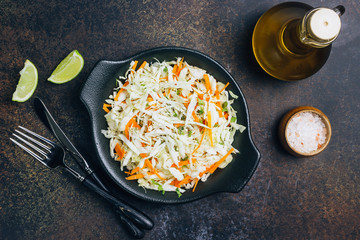 Fresh coleslaw salad in black plate on dark background.