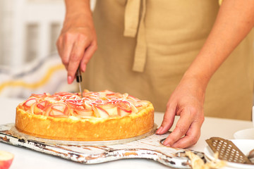 Obraz na płótnie Canvas Sweet homemade pie ready to eating. Whole apple pie and a piece is taken out with a cake server. Tasty apple cake served for dessert. Traditional apple pie with cinnamon.