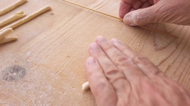 Pasta fatta in casa su un tagliere di legno con farina bianca e integrale.