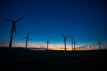 Obraz premium Power generators of windmills at shadow sunset - Wind turbine on field at sunset