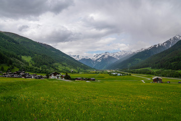 Picturesque village withg green meadow and old historic mountain chaletes in the Swiss Alps. Lush green grass and meadow flowers. Old historic chaletes in mountain village on the background.