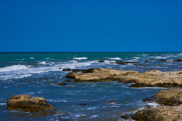 Panorama landscape scenic view of isolated deserted rocky beach with blue turquoise sea water and sky with white clouds and mountain background on beautiful and colorful Mallorca island in Spain.