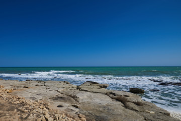 Fototapeta na wymiar Summer landscape. Rocky coastline with a cove and rock, split view above water surface, Mediterranean sea, Spain. Azure sea, wave and blue sky. Seascape with sea horizon and clear deep blue sky.