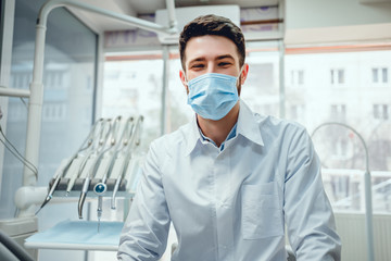 Fototapeta na wymiar Portrait of a male dentist in mask in his clinic.