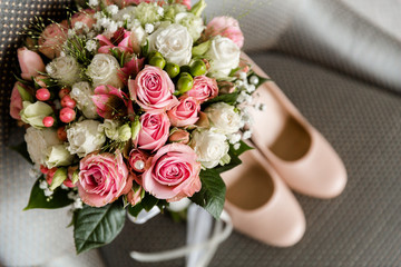 Wedding bouquet of white and pink roses on a blurred background of the bride's shoes