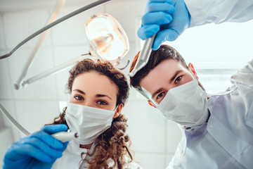 Low angle portrait of male and female dentists wearing masks at dental clinic. - Powered by Adobe