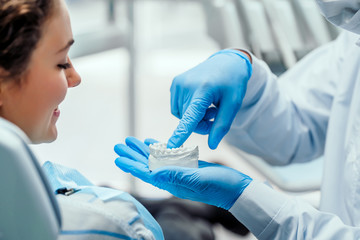 Dentist explaining the details of dental mold to his patient. Close up view.