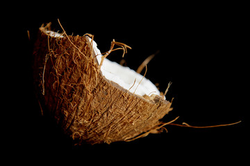 ripe coconut is broken into two halves isolated on a black background close-up. the insides of the tropical palm fetus