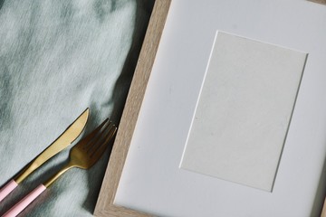 Mockup-template. Photo frame on pastel fabric. Chopsticks, fork, spoon and knife on frame, with white copy space, cozy feeling ideal for Asian and Western food/beverage shoot-out.