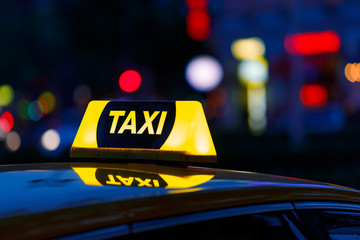 Yellow taxi cab and blurred city lights background at night with colorful bokeh