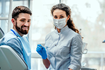 View of a young attractive dentist explaning his work to a patient.
