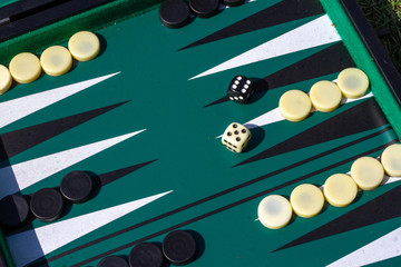 Backgammon set with green felt in beginning set up with different colored dice showing a five and a...