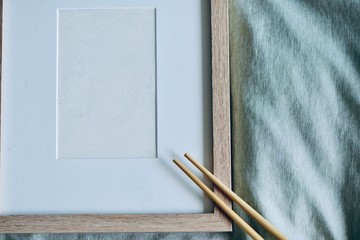 Mockup-template. Photo frame in bed. Wooden chopsticks on frame, with white copy space, cozy feeling ideal for Asian food/beverage shoot-out.