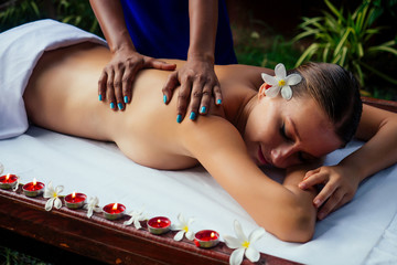 Fototapeta na wymiar Ayurveda indian woman having relaxing body asia spa treatment india flowers and candles