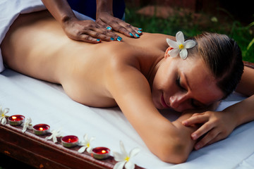 Obraz na płótnie Canvas Ayurveda indian woman having relaxing body asia spa treatment india flowers and candles