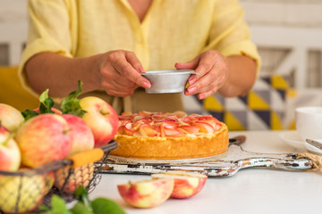 Apple shaped roses cake on rustic wooden table. Sweet apple dessert pie. Female hands cooking cake on wooden table. Homemade cooking and cozy home concept.