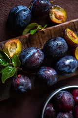 Fresh plums in drops with leaves. Fruits. On a dark wooden background. Top view. Free space for your text. Toned image. Selective focus.