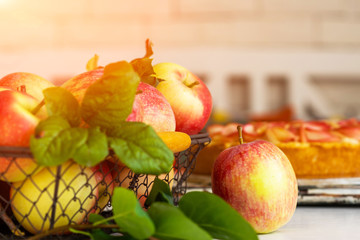 Ripe organic apples in vintage basket on rustic white table. Apple cheesecake in the background. Summer homemade apple tart with ingredients. Healthy organic food. Tasty breakfast.