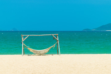 Hammock on beach of island with yellow sand and blue ocean