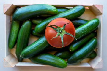 Tomatoes and cucumbers in a wooden crate. Concept- fresh organic vegetables, healthy food from garden. Selective focus.