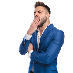 tired man in suit yawning with hand at mouth