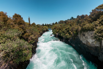 Powerful River in New Zealand - water surging through a deep river, surrounded in trees and rocks.