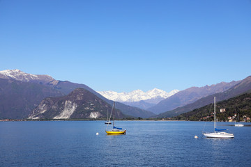Fototapeta na wymiar Maggiore lake with sailing boats panoramic view. Piedmont Italy Europe. Lake with sailing boats and view of snow rocky massif at spring or summer time. Travel and vacation concept.- Image