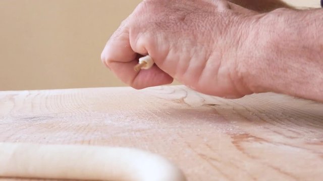 Mani di uno chef stanno preparando la pasta fatta in casa su un tagliere di legno con farina di semola e integrale.