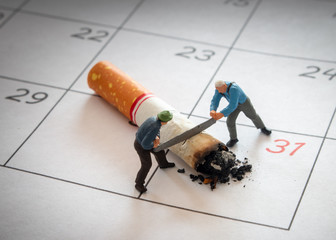 Miniature figure Workers are chopping cigarette with saw