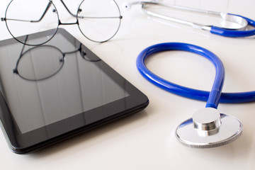 Stethoscope, digital tablet and eyeglasses on white background. Medical equipment.