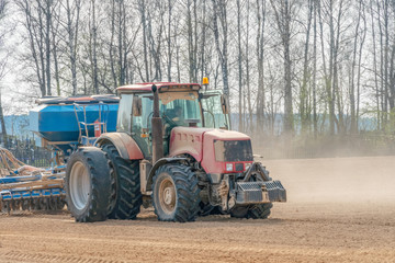 Farmer in tractor preparing land with seedbed cultivator as part of pre seeding activities in early spring season of agricultural works at farmlands.