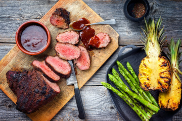 Barbecue dry aged wagyu tri tip steak with grilled pineapples and green asparagus top view on a...